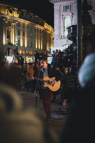 guitar man in black t-shirt playing guitar on street during night time leisure activities